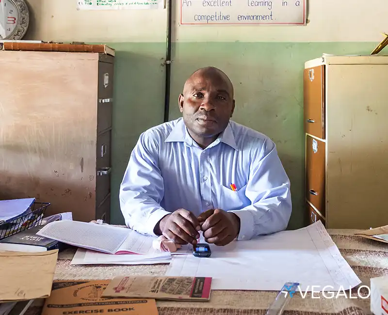 Headmaster sitting in his office in front of a cluttered desk in Zambia