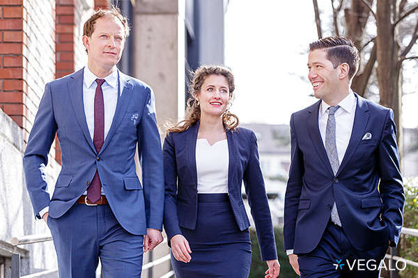 three business people dressed in suits walking and talking together